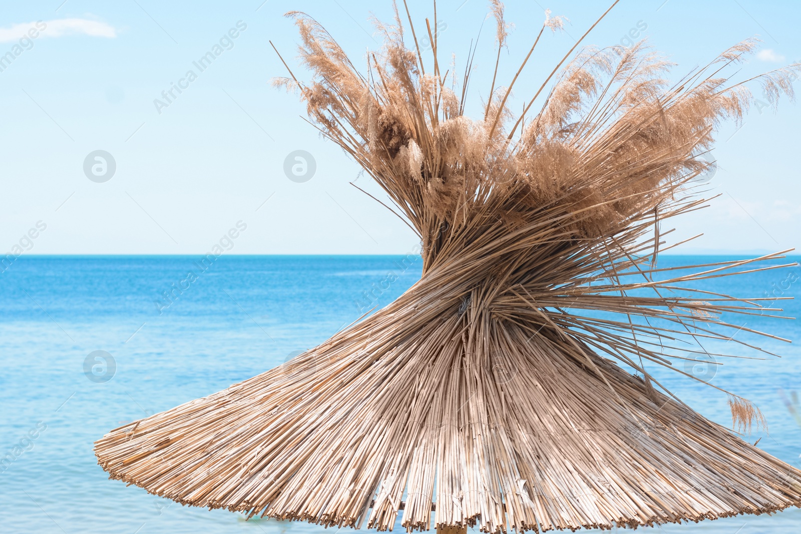 Photo of Beautiful straw beach umbrella against blue sky