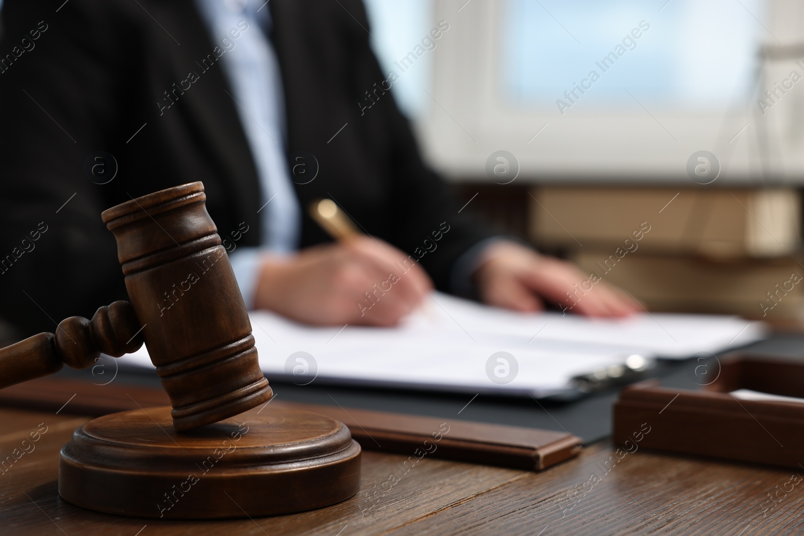 Photo of Lawyer working with documents at wooden table indoors, focus on gavel