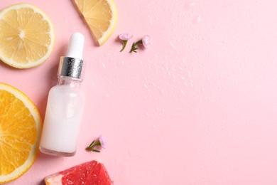 Photo of Bottle of cosmetic serum, sliced citrus fruits and small flowers on wet pink background, flat lay. Space for text