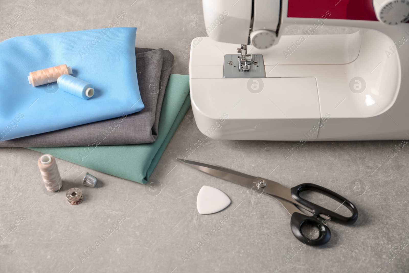 Photo of Sewing machine, fabrics and accessories for tailoring on table