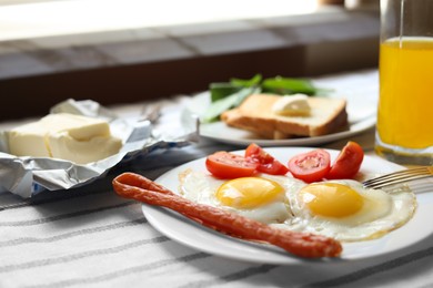 Photo of Tasty fried eggs with smoked sausages and tomatoes on table, closeup