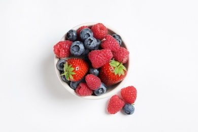 Photo of Bowl with raspberries, strawberries and blueberries on white background