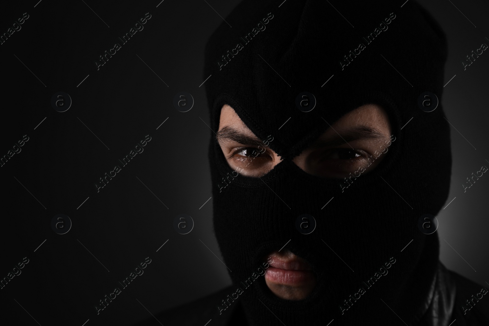 Photo of Man wearing knitted balaclava on black background, closeup. Space for text