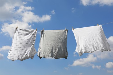 Photo of Washing line with clean clothes against sky. Drying laundry outside