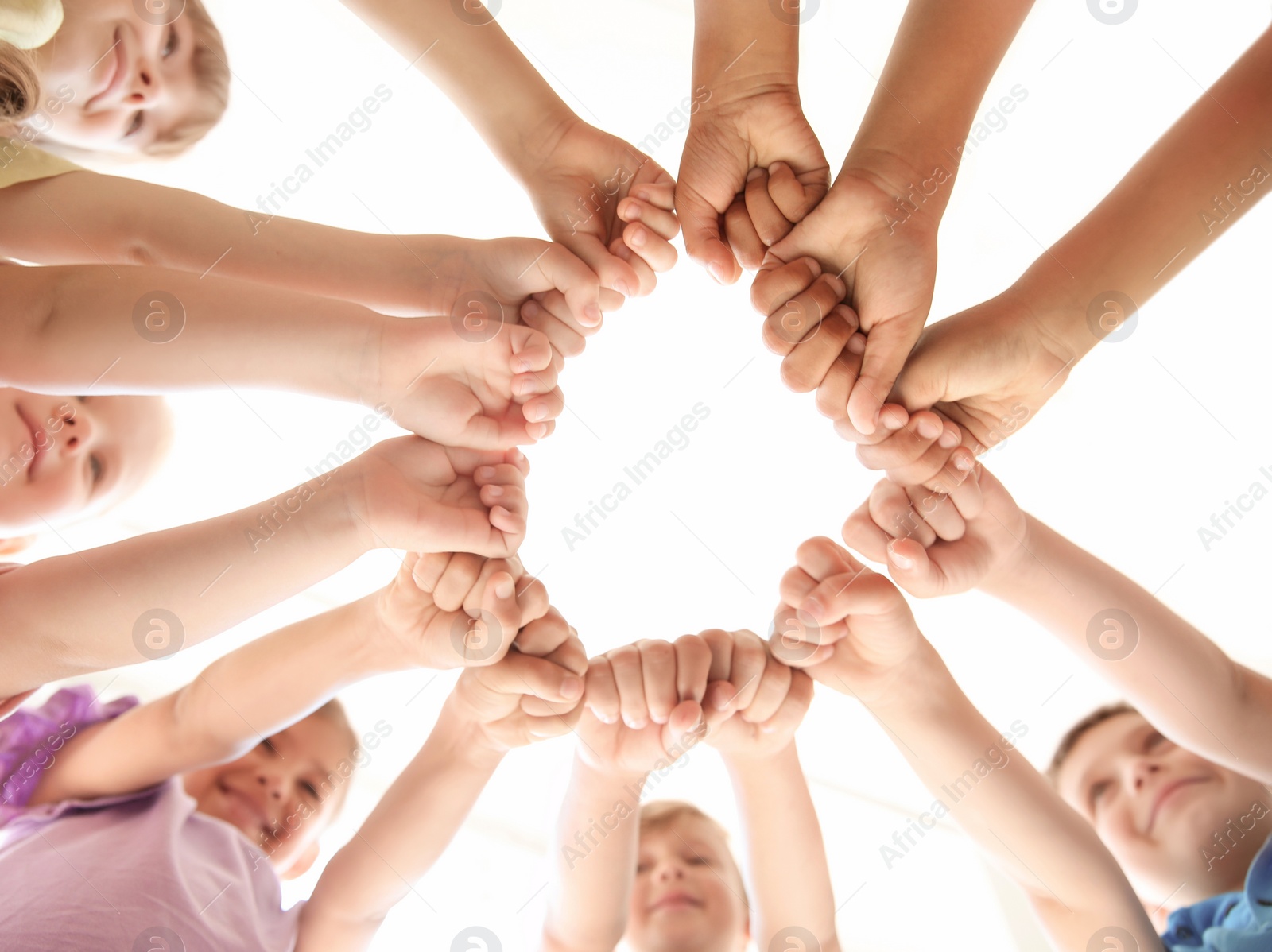 Photo of Little children putting their hands together indoors, view from below. Unity concept