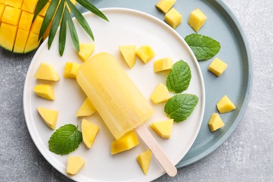 Photo of Plate of tasty mango ice pop on grey table, flat lay. Fruit popsicle