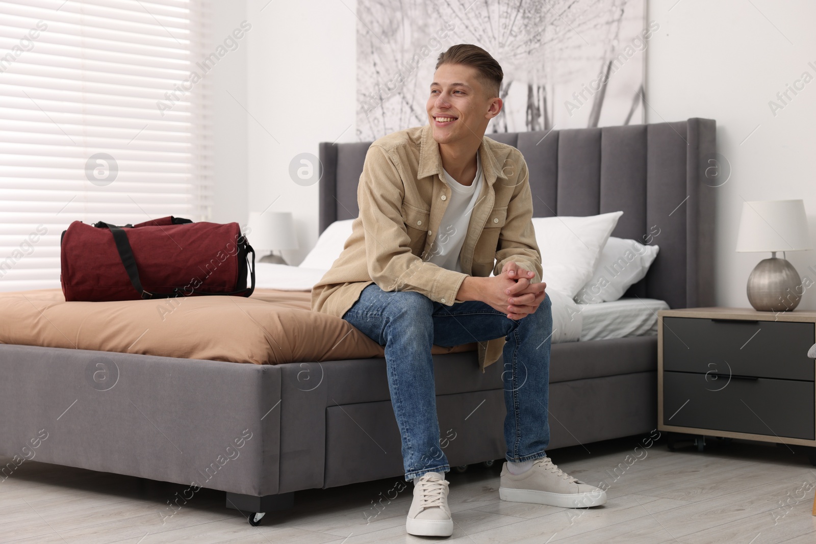 Photo of Smiling guest relaxing on bed in stylish hotel room