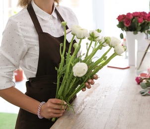 Photo of Female florist holding beautiful flowers in shop