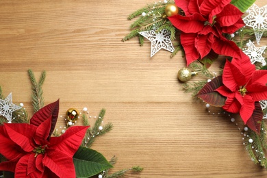 Photo of Flat lay composition with poinsettias (traditional Christmas flowers) and holiday decor on wooden table. Space for text