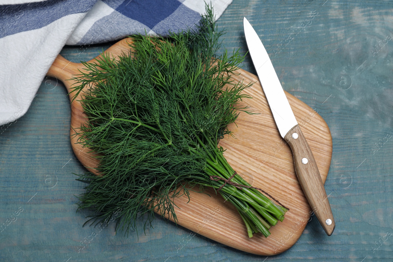 Photo of Bunch of fresh dill on light blue wooden table, flat lay