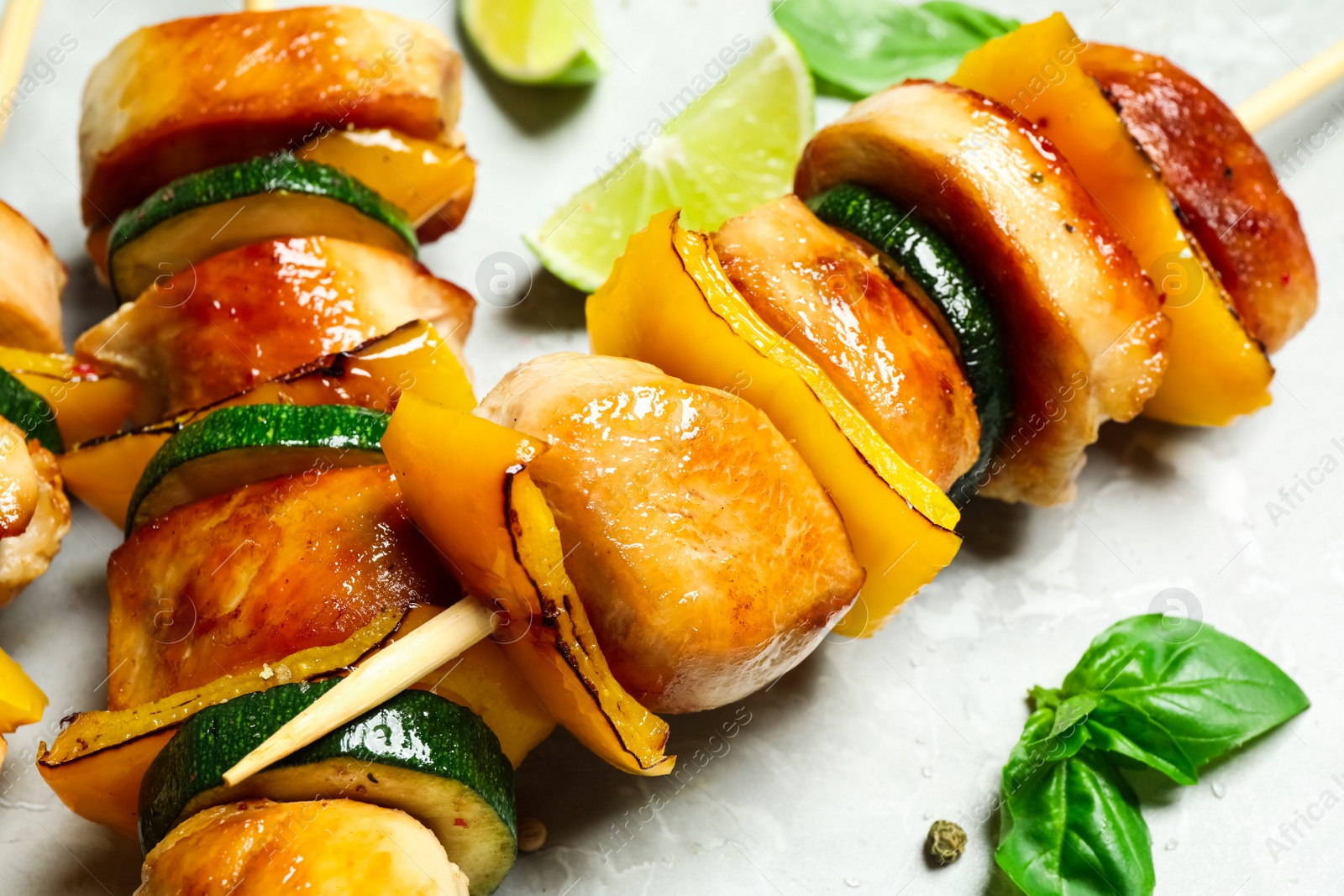 Photo of Delicious chicken shish kebabs with vegetables on grey marble table, closeup