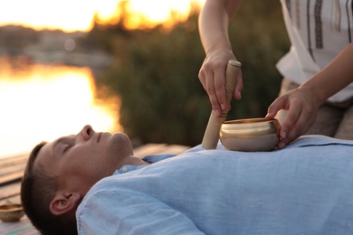 Man at healing session with singing bowl outdoors
