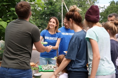 Photo of Volunteers serving food for poor people outdoors