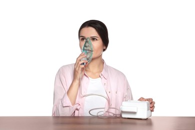 Photo of Young woman using nebulizer at wooden table on white background