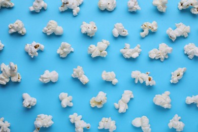 Photo of Tasty popcorn on light blue background, flat lay