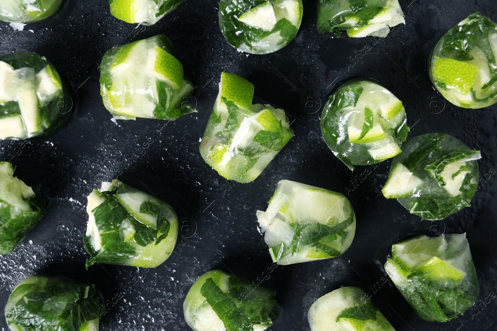 Photo of Lime and mint ice cubes on dark background, flat lay