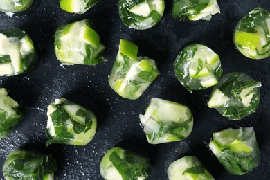 Lime and mint ice cubes on dark background, flat lay