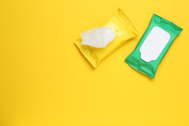 Photo of Wet wipes flow packs on yellow background, flat lay. Space for text