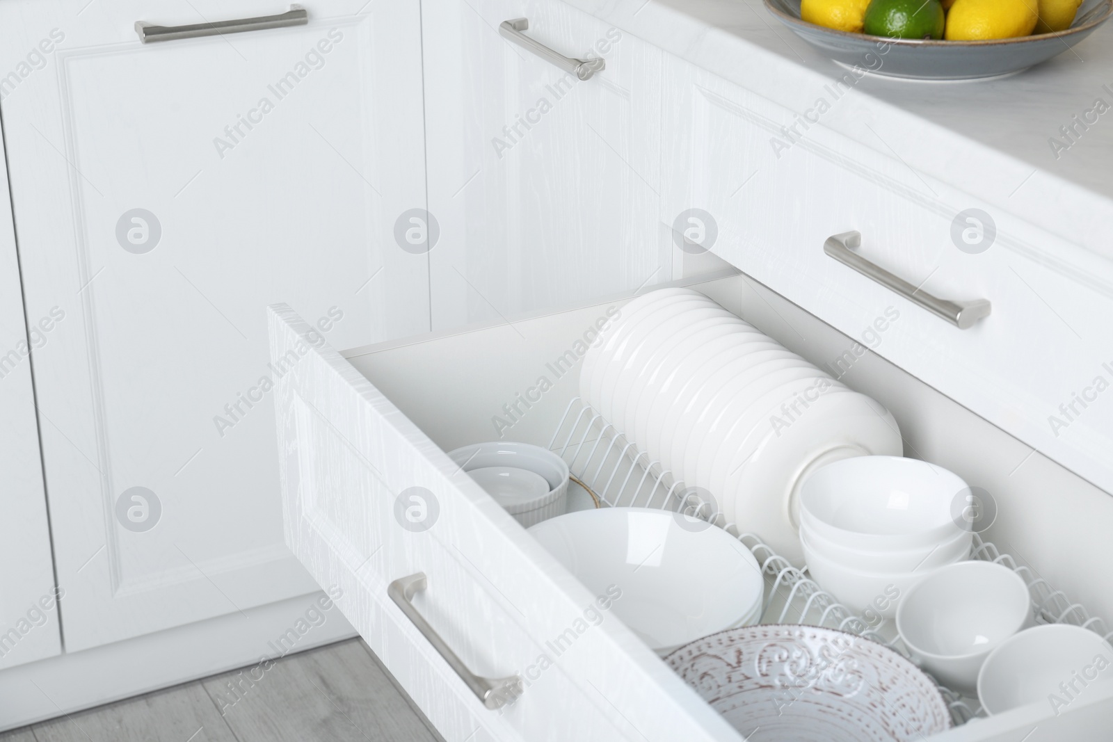 Photo of Open drawer with different plates and bowls in kitchen