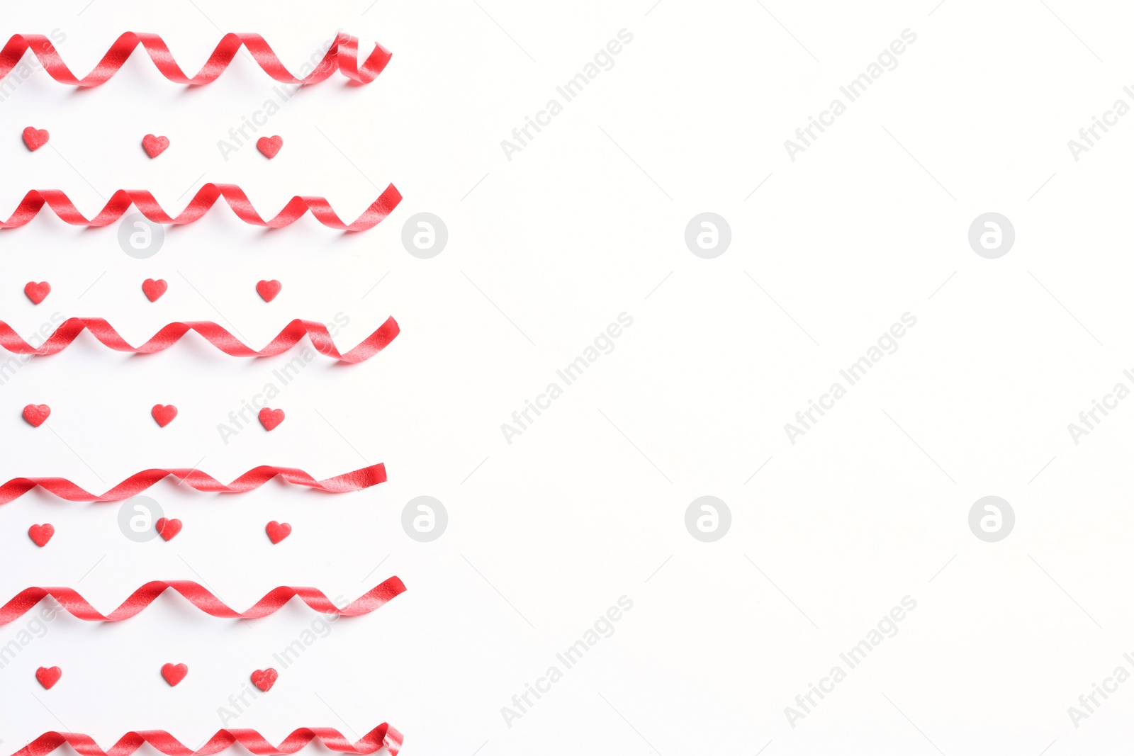 Photo of Red serpentine streamers and heart shaped confetti on white background, top view