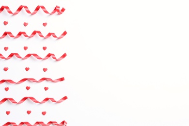 Photo of Red serpentine streamers and heart shaped confetti on white background, top view