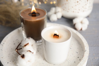 Burning candles with wooden wicks and cotton flower on tray