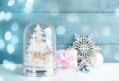 Image of Beautiful Christmas snow globe, gift box and decor on light table, bokeh effect