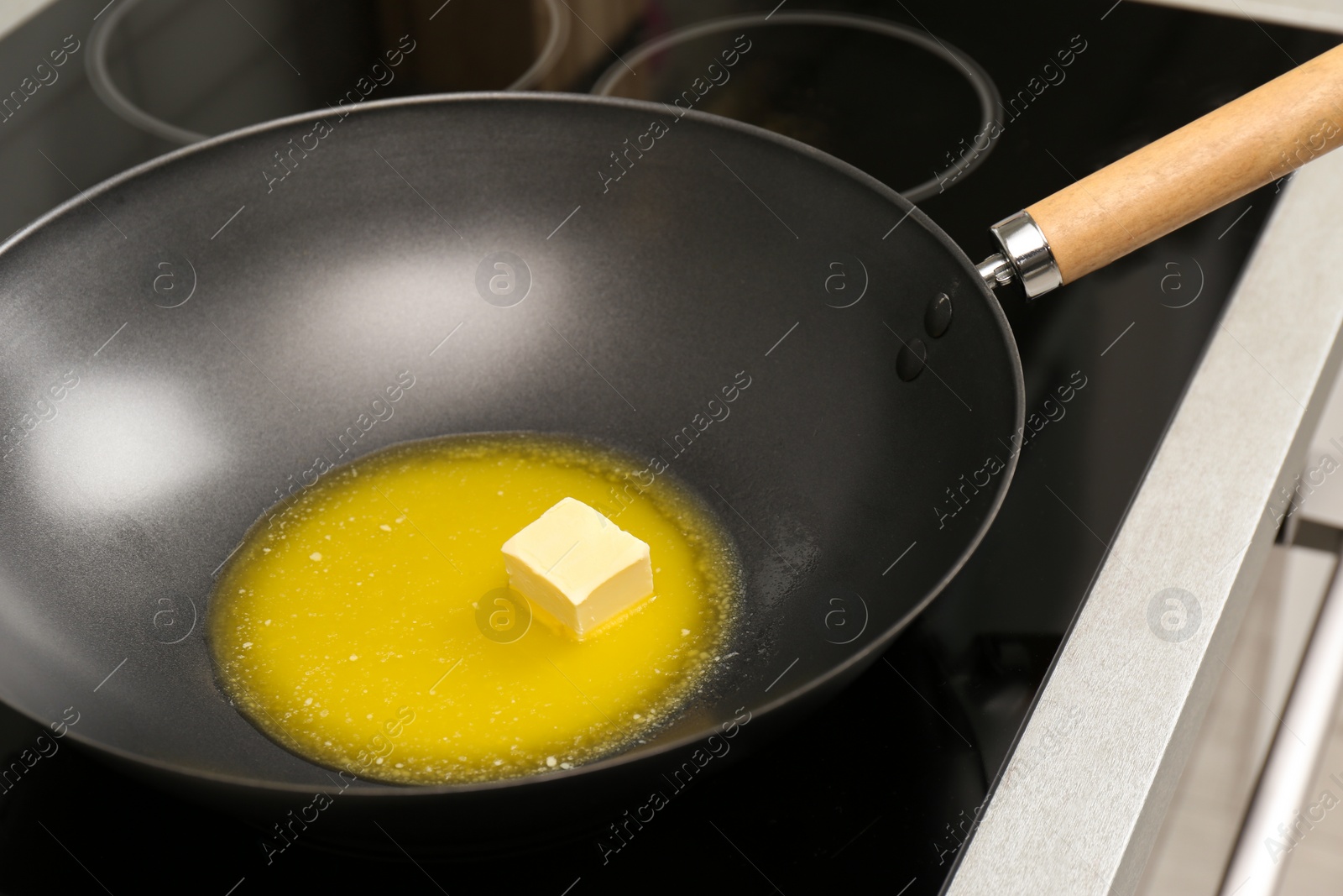 Photo of Wok pan with melted butter on stove