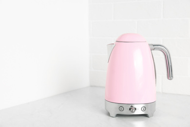 Photo of Modern electric kettle on counter in kitchen. Space for text