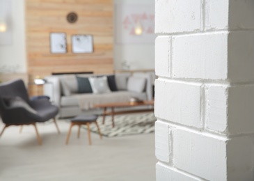 Photo of White brick wall and blurred living room interior on background