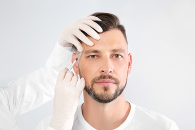 Mature man getting facial injection on white background. Cosmetic surgery concept