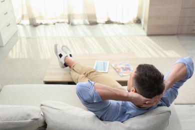 Man relaxing on sofa at home, above view