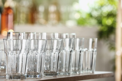 Photo of Empty glasses on wooden table against blurred background