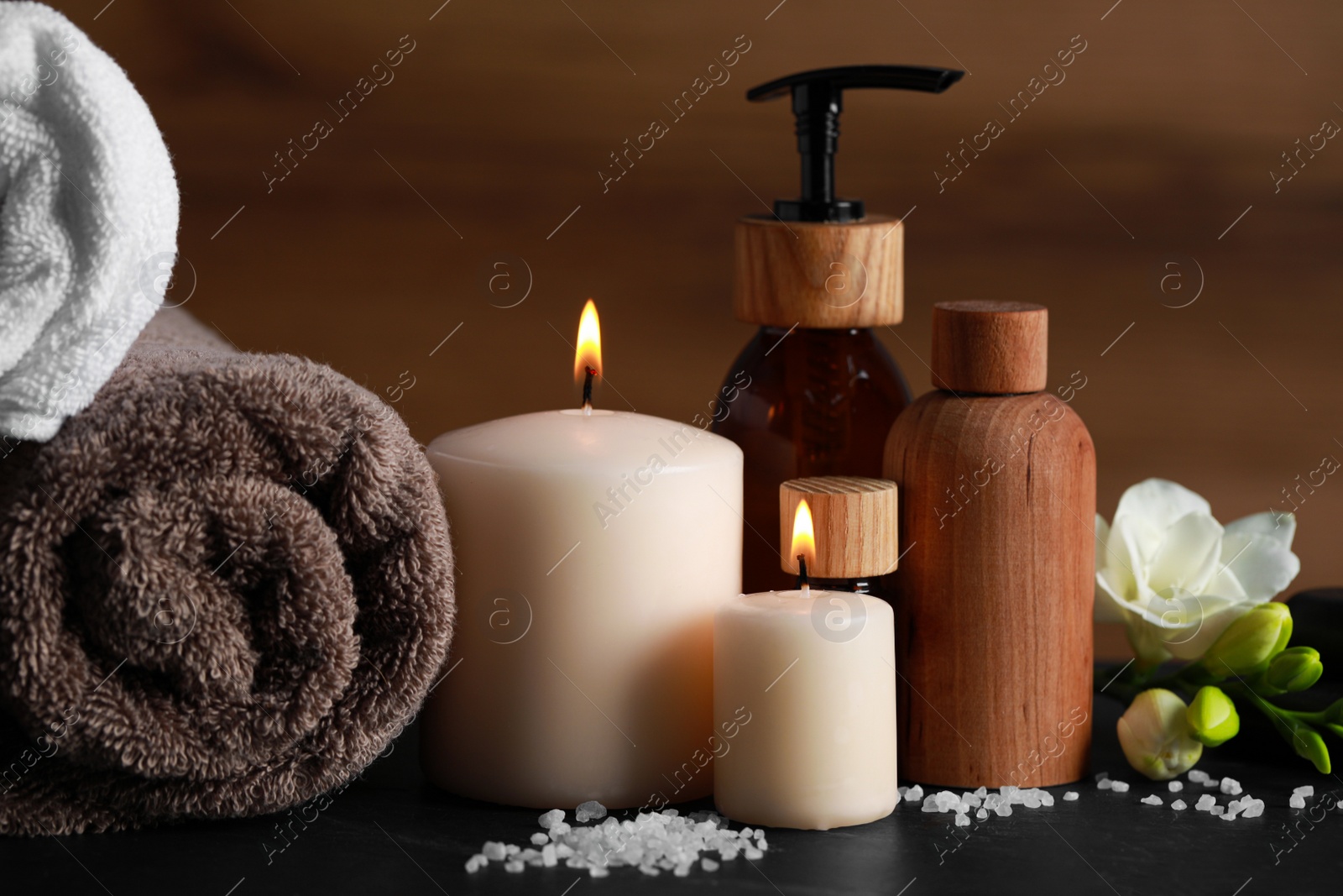 Photo of Beautiful spa composition with different care products and burning candles on black table