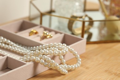 Photo of Jewelry box with many different accessories on wooden table, closeup