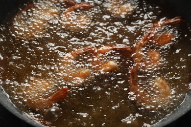 Photo of Cooking delicious shrimps in hot oil, closeup