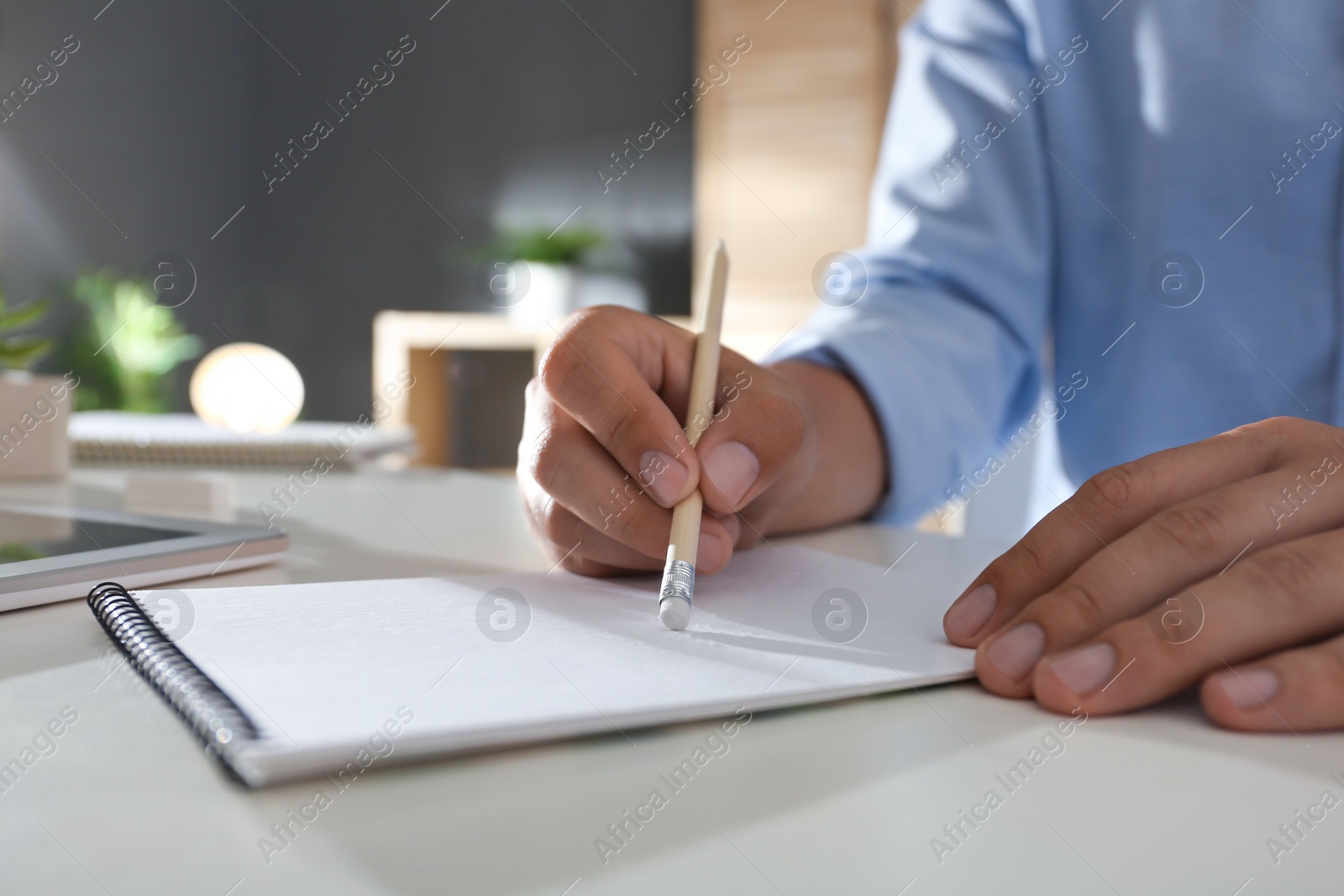 Photo of Man correcting picture on paper with pencil eraser at table, closeup