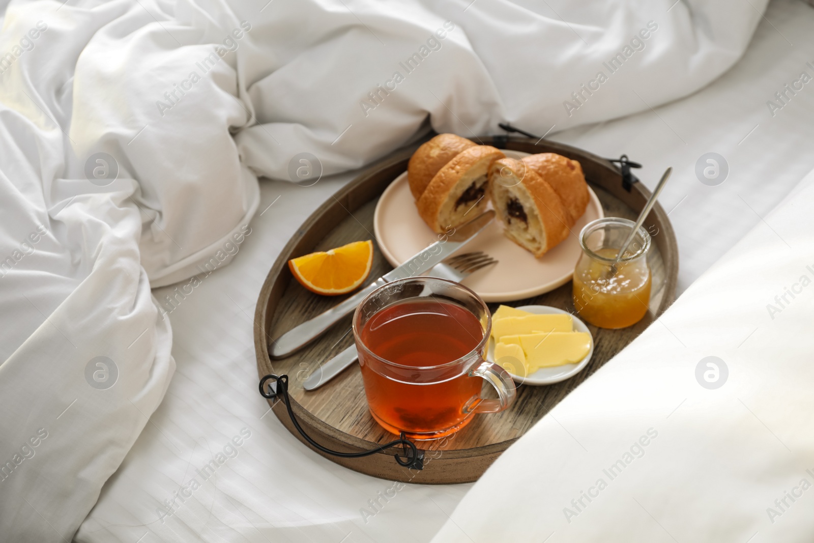 Photo of Tray with tasty breakfast on bed in morning