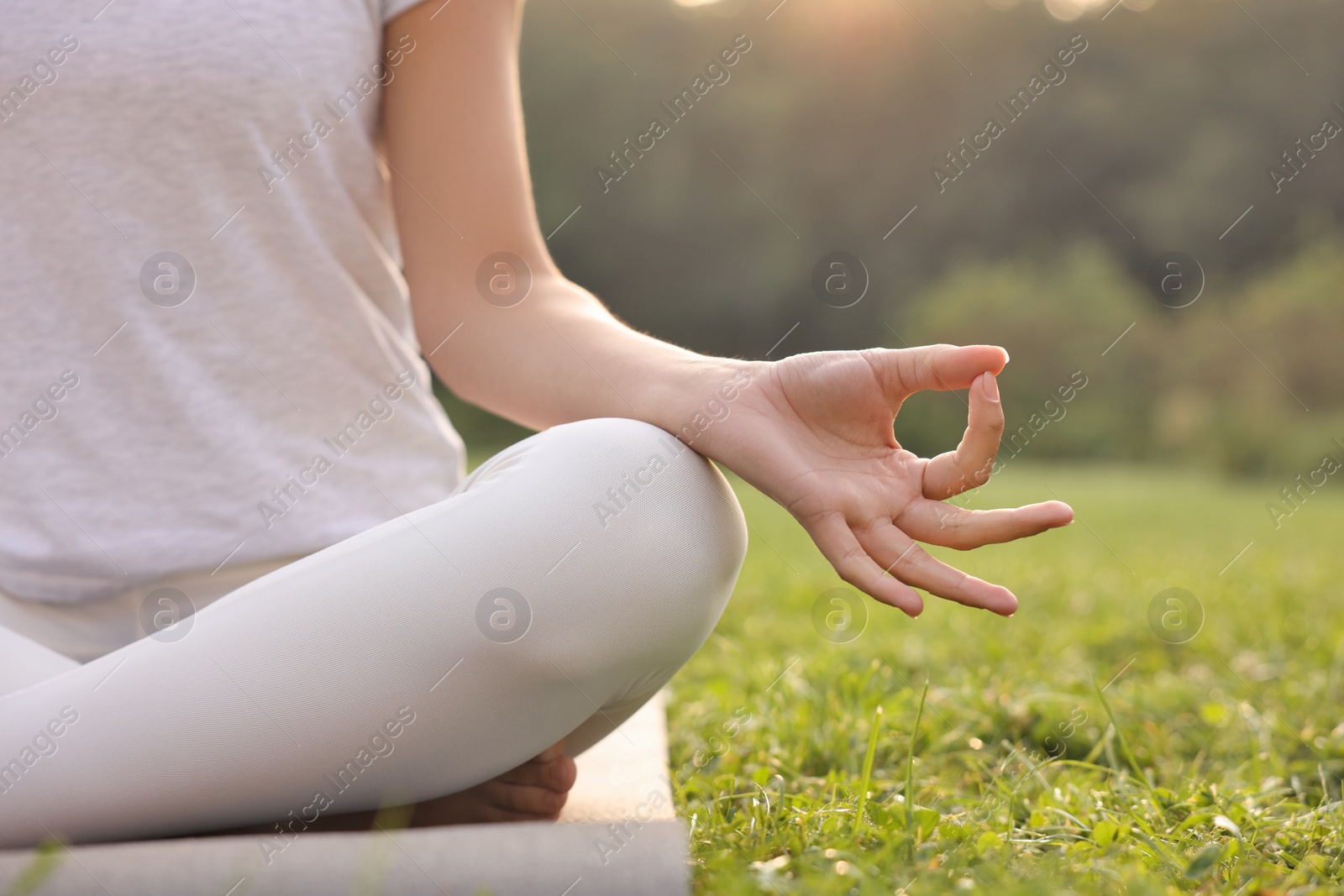 Photo of Woman practicing yoga on mat outdoors, closeup and space for text. Lotus pose