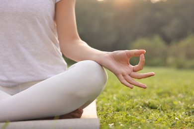 Woman practicing yoga on mat outdoors, closeup and space for text. Lotus pose