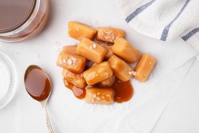 Yummy caramel candies and sea salt on white table, flat lay