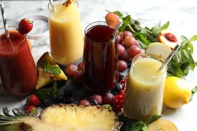 Photo of Glasses of delicious juices and fresh ingredients on white table