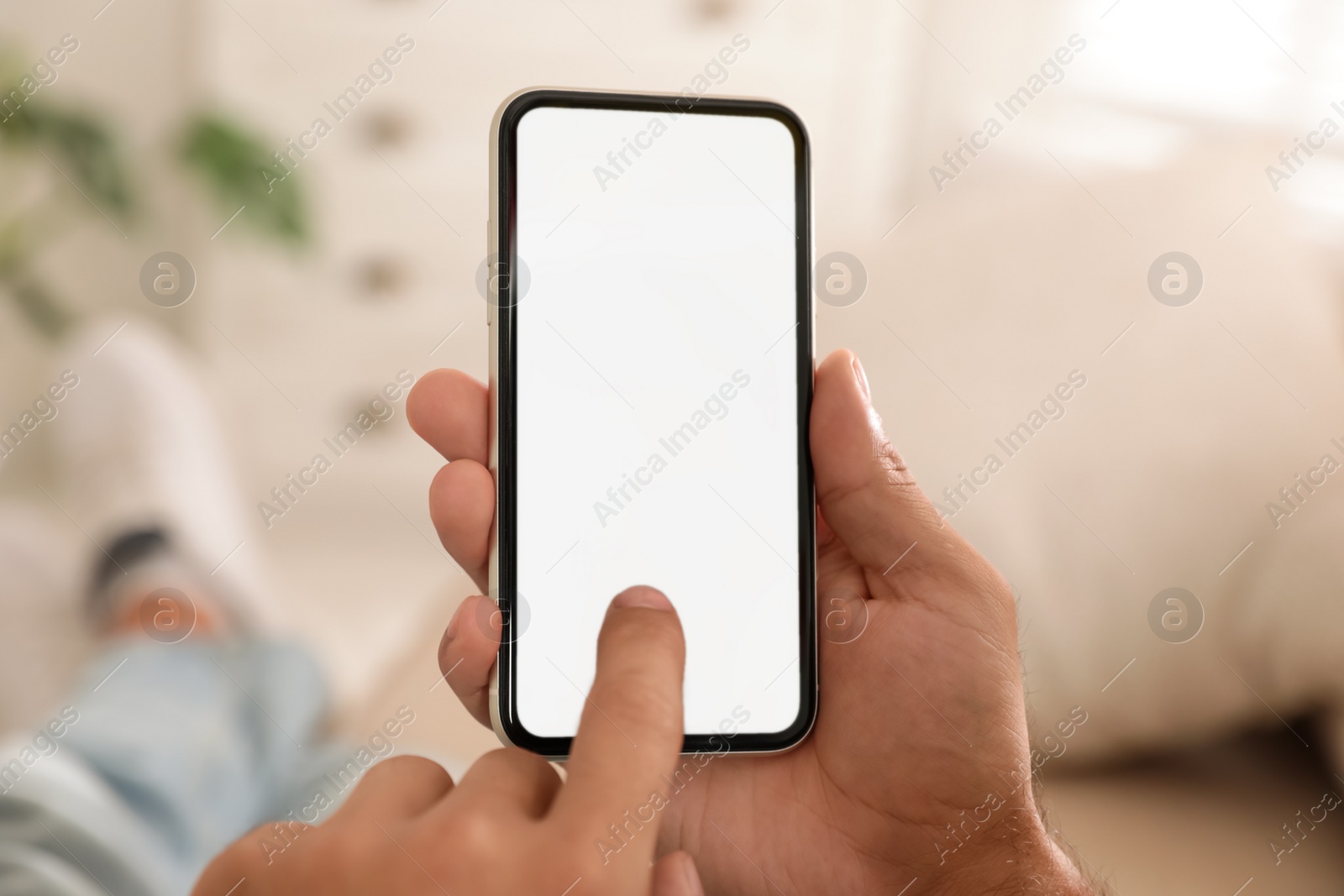 Photo of Man using mobile phone with empty screen indoors, closeup