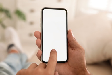 Man using mobile phone with empty screen indoors, closeup