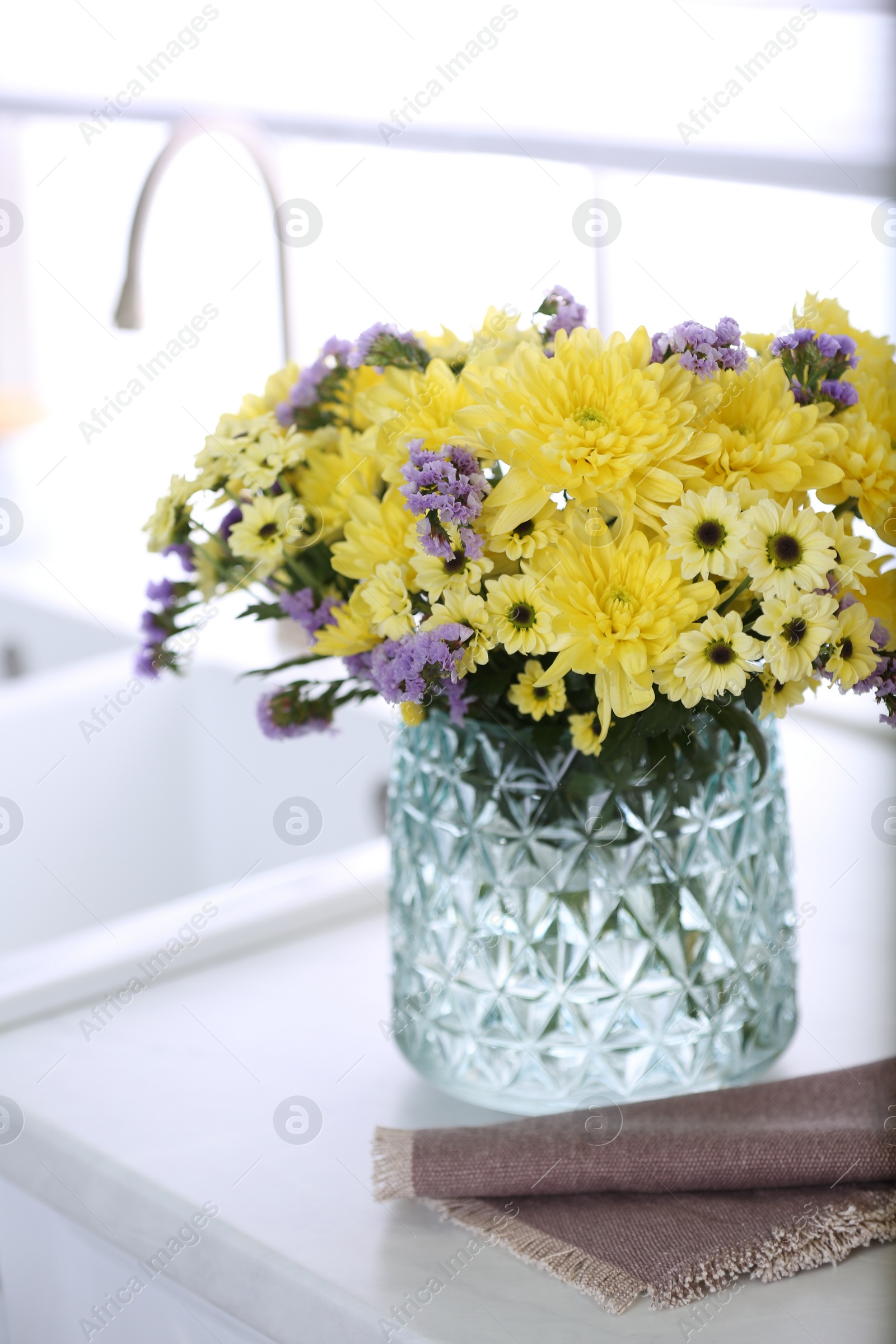 Photo of Vase with beautiful chrysanthemum flowers on countertop in kitchen. Interior design