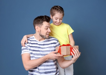 Photo of Man receiving gift for Father's Day from his daughter on color background