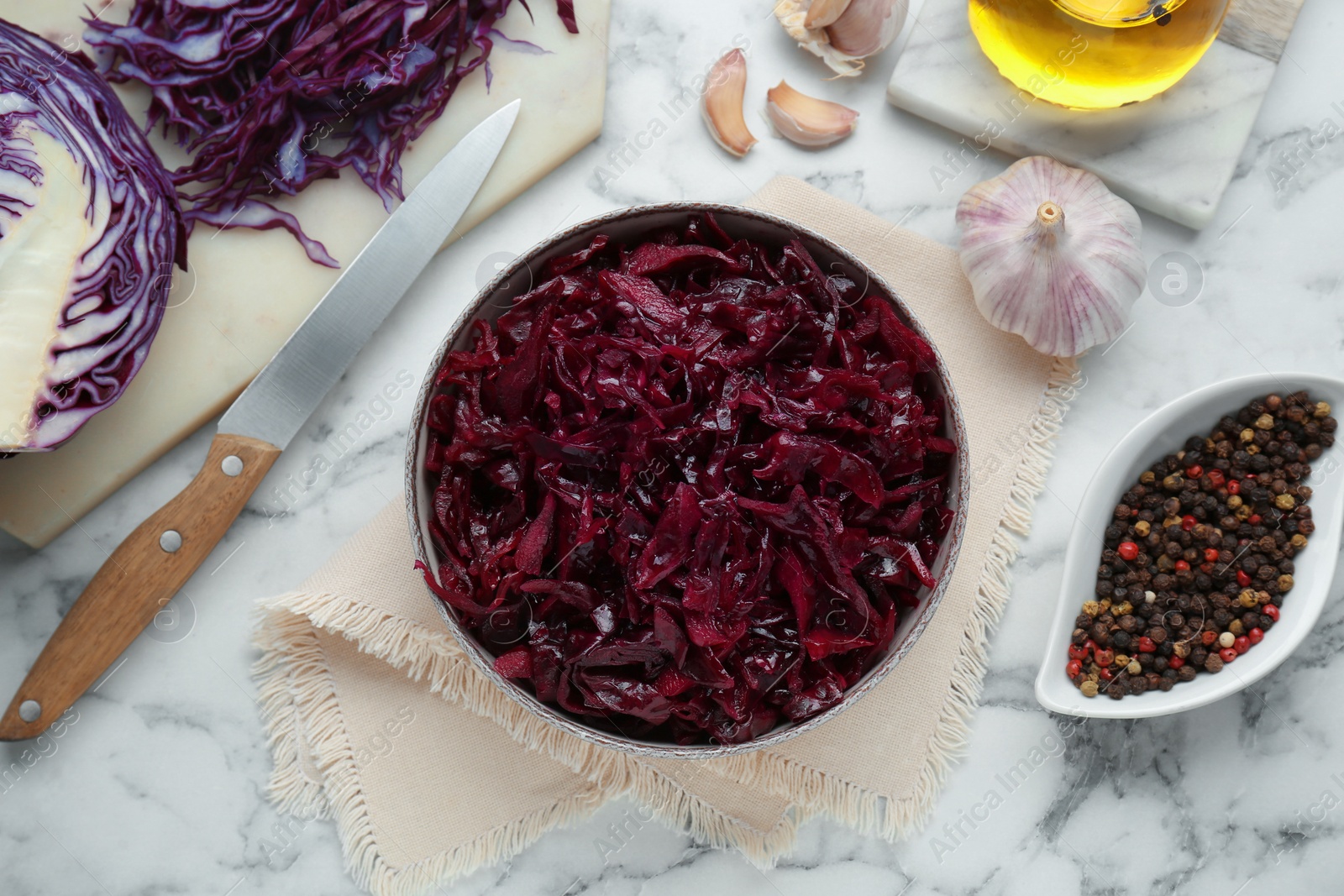 Photo of Tasty red cabbage sauerkraut and ingredients on white marble table, flat lay