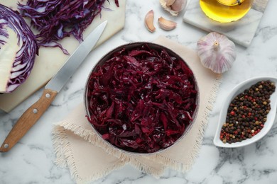 Photo of Tasty red cabbage sauerkraut and ingredients on white marble table, flat lay