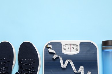 Photo of Weight loss concept. Flat lay composition with sneakers, scales and measuring tape on light blue background, space for text