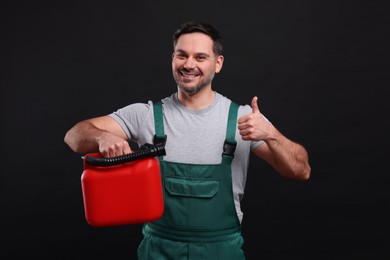 Photo of Man holding red canister and showing thumbs up on black background